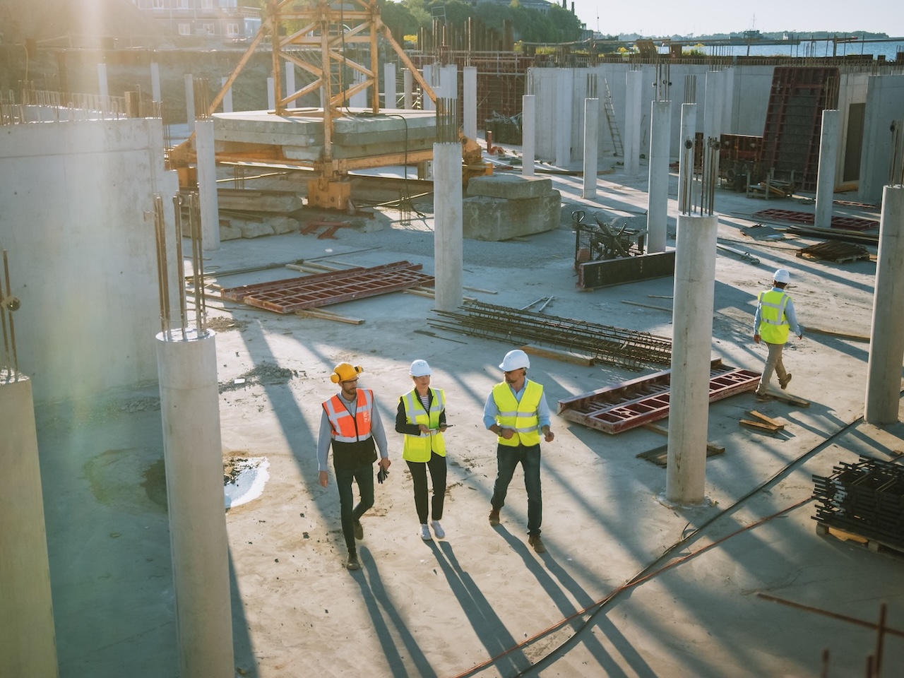 AdobeStock_378798786 Diverse Team of Specialists Taking a Walk Through Construction Site. Real Estate Building Project with Senior Civil Engineer, Architect, General Worker Discussing Planning and Development Details.